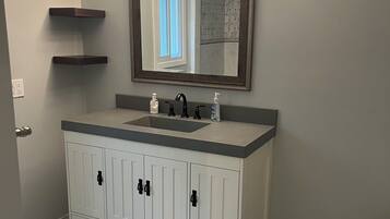 A bathroom with a white vanity, a mirror, and a toilet.