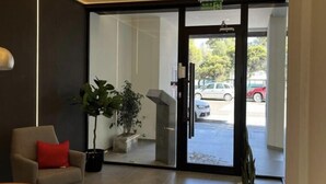 A modern reception area with a glass door leading outside, a potted plant, and a seating area with a chair and a table.