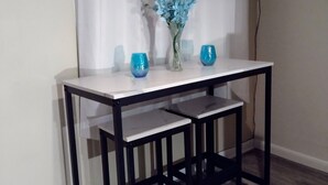 A small dining table with two chairs, a vase with blue flowers, and two blue glasses on the table. - TRAVELERS! In the heart of Baraboo, close to SSM Hospital! (Baraboo)