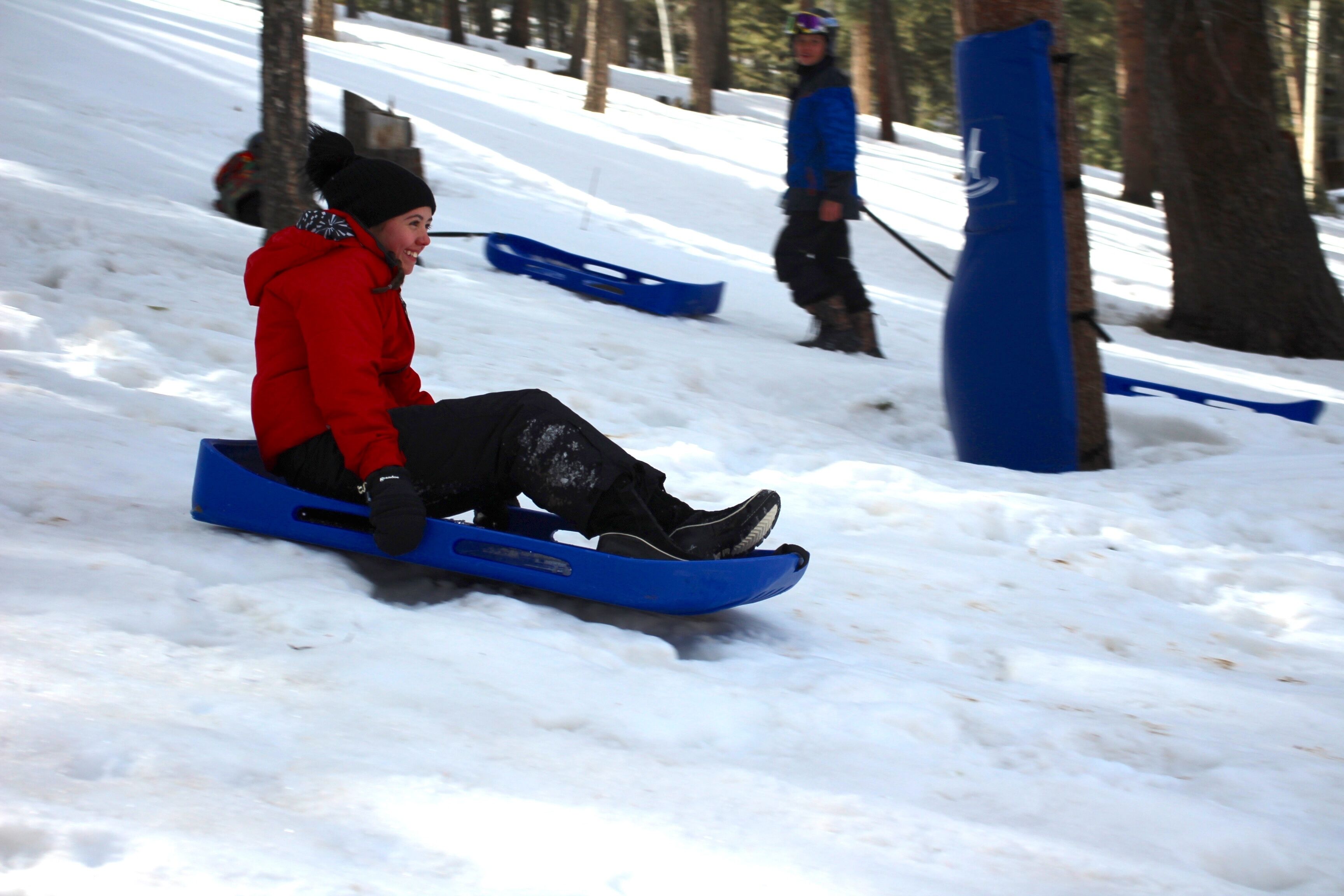 Une personne dévale une pente enneigée sur une luge.