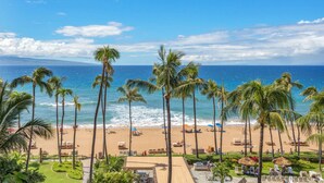 A beach view with palm trees, a sandy beach, and the ocean.