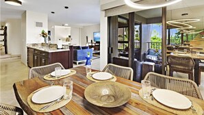 A modern dining area with a wooden table set for four, surrounded by wicker chairs.