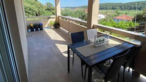 A balcony with a table and chairs, a view of the countryside, and exercise balls against the wall. - Holiday apartment with balcony (Kampor)
