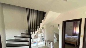 A modern interior with a black and white staircase, a white storage unit, and a bed in the adjacent room. - Holiday apartment with balcony (Kampor)
