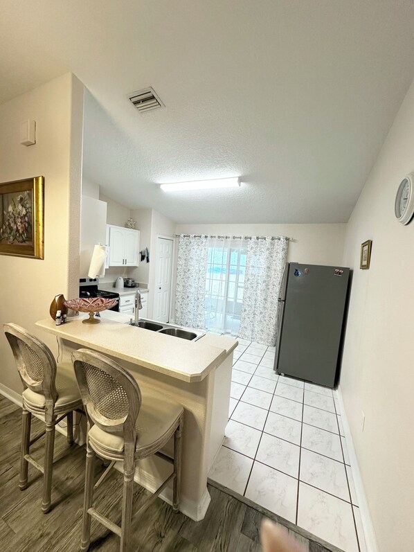 Una cocina compacta con una isla central, armarios blancos y un refrigerador.