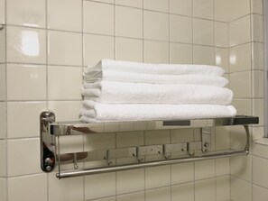 Un bagno con un porta asciugamani pieno di diversi asciugamani bianchi piegati con cura.