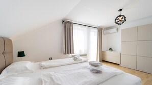 Une chambre d’hôtel moderne avec un grand lit, une table de chevet, une lampe, une fenêtre avec des rideaux et un luminaire au plafond.