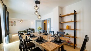 Un coin repas avec une table en bois dressée pour deux personnes, des chaises noires et un luminaire suspendu moderne.