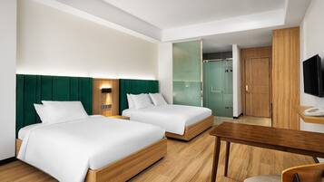 Habitación de hotel con dos camas, un escritorio, una silla y un televisor.