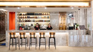A bar area with a marble counter, multiple stools, and a variety of bottles on shelves. - Grand Pailin Casino & Resort (Sala Krau)