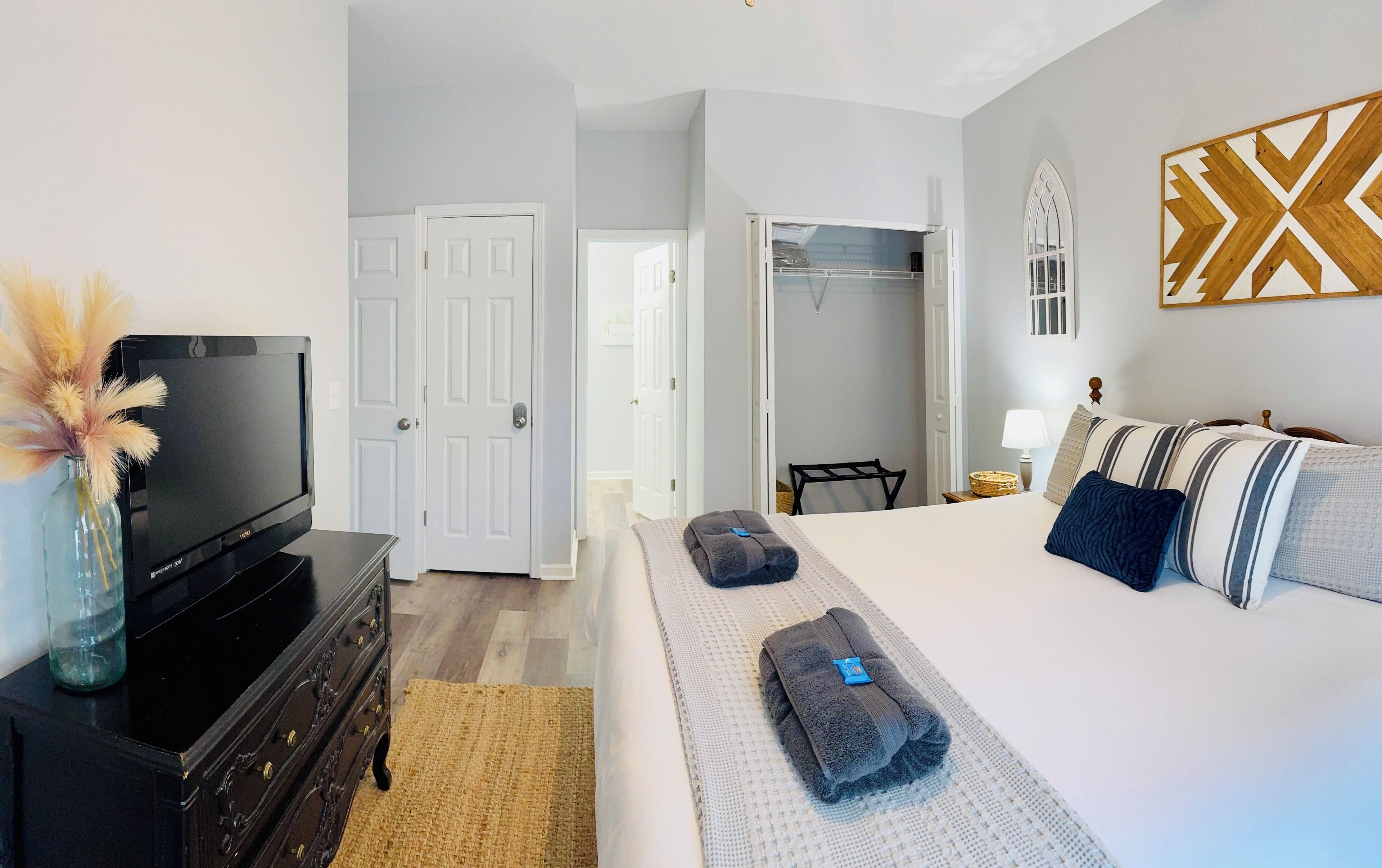 A hotel room with a bed, a TV, a dresser, and a wardrobe.