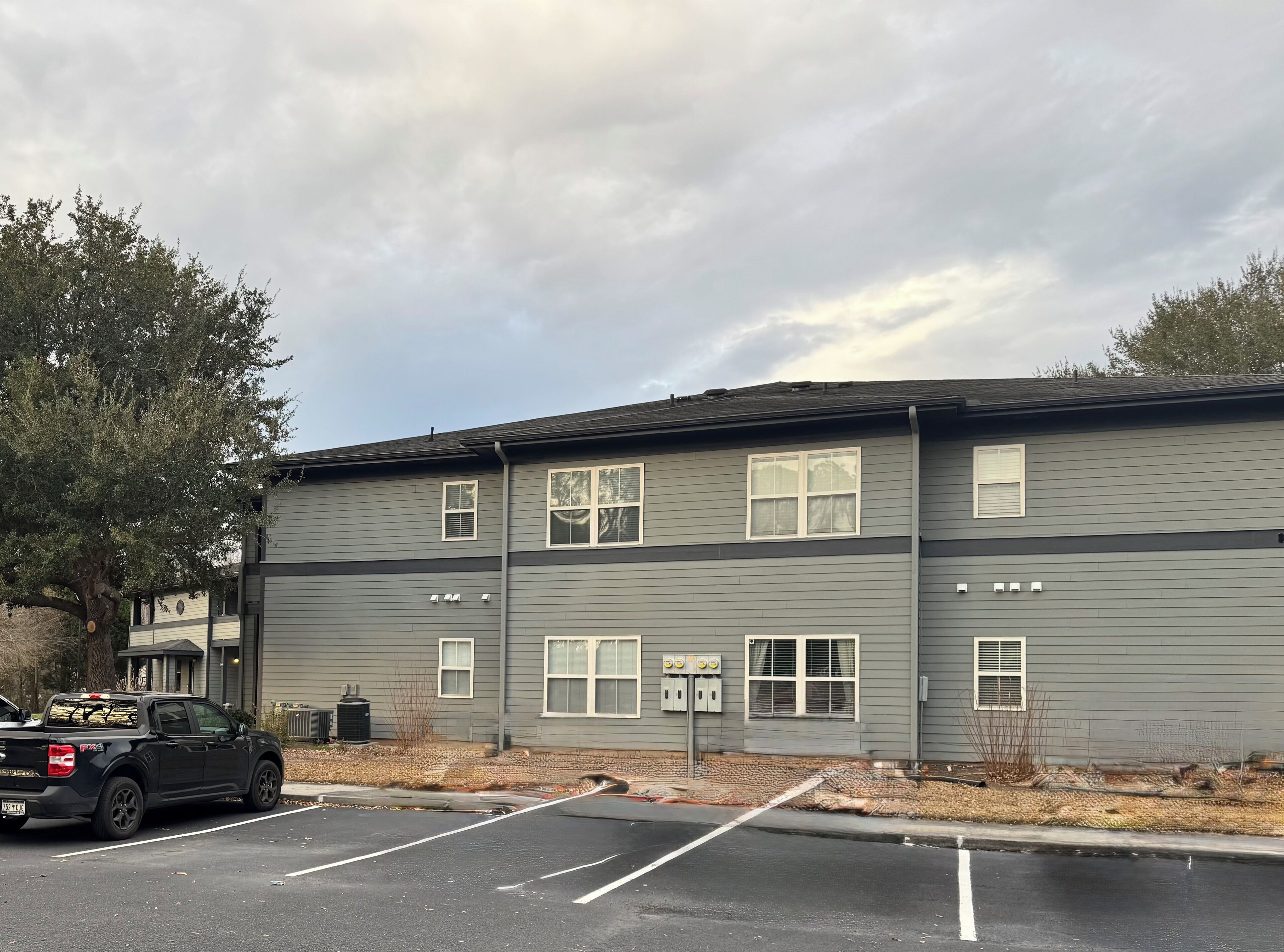 A two-story building with a parking lot in front.