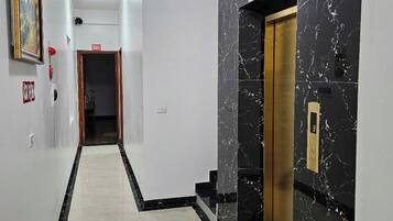 A hallway with a marble wall, a red bench, and an elevator.