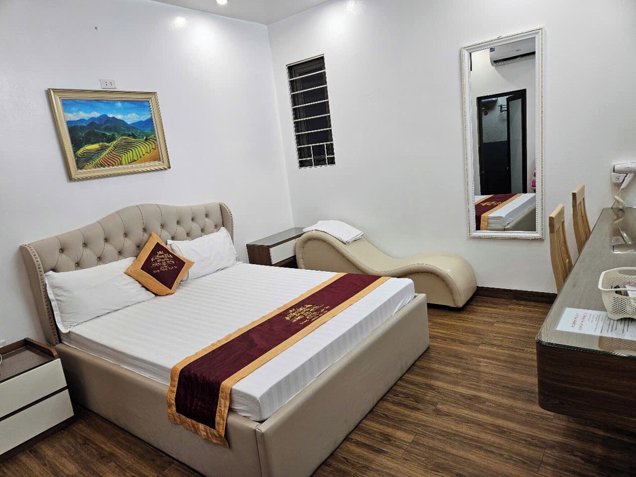 Een hotelkamer met een groot bed, een massagestoel, een klein tafeltje en een raam met zonwering.