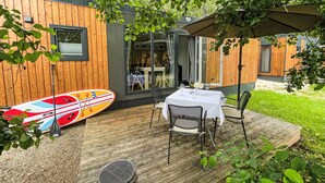 A wooden deck with a table and chairs, a surfboard, and a grill. - Tiny Haus Antonia by Interhome (Riedenburg)