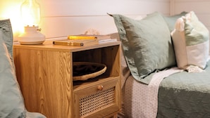 A wooden bedside table with a lamp, books, and a basket.