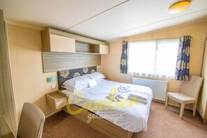 Une chambre bien rangée, avec un lit, des tables de chevet, une chaise et une fenêtre avec des rideaux.