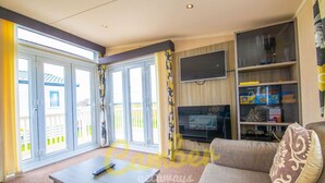 Ein Wohnzimmer mit einer Couch, einem Couchtisch, einem an der Wand befestigten Fernseher und einem Bücherregal.