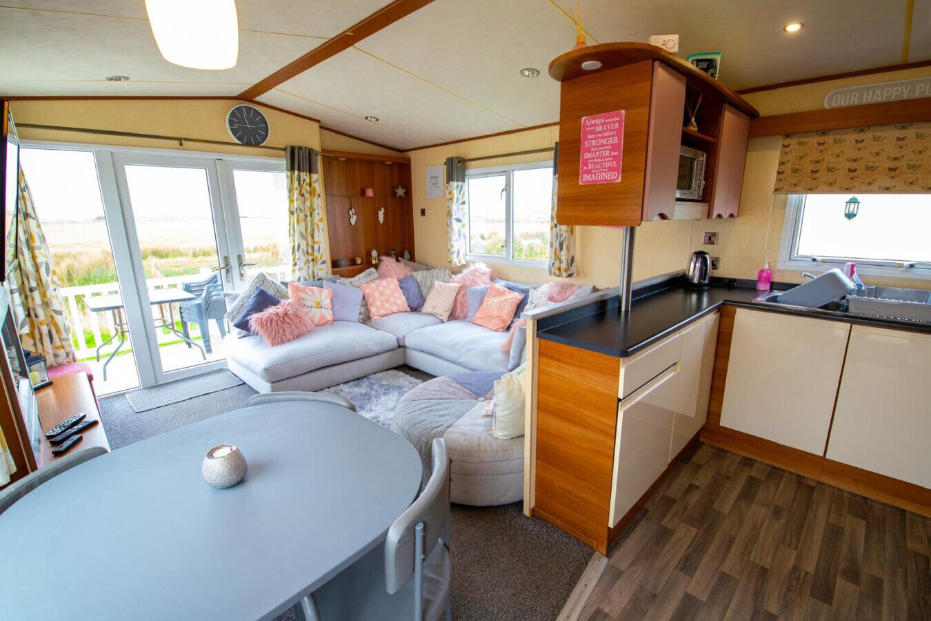 Ein gemütliches Wohnmobil-Interieur mit Essbereich, einer Küchenzeile und einer Wohnfläche inklusive Sofa und Kissen.