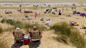 Une plage où des gens se détendent sous des parasols et sur des chaises longues.
