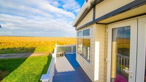 A mobile home with a deck and large windows overlooking a field.