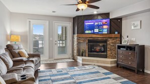 A living room with a fireplace, a sofa, a TV, and a ceiling fan. - Dells Lake Villa - Lake Front Luxury (Wisconsin Dells)