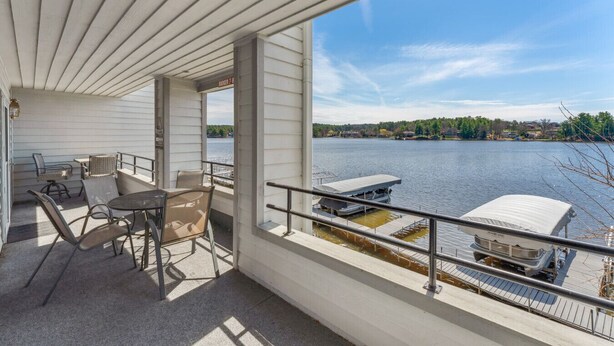 A covered outdoor area with a table and chairs, a view of a lake, and docked boats. - Dells Lake Villa - Lake Front Luxury (Wisconsin Dells)