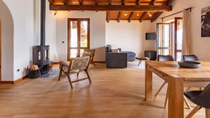 Un vaste espace de vie doté d’un plafond en bois, d’une cheminée, d’un canapé et d’une table à manger.