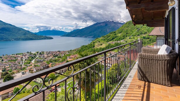Un balcon avec vue sur un lac, des montagnes et une ville.