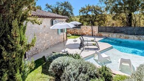 Une maison en pierre avec une piscine, du mobilier d’extérieur et un mur en pierre.