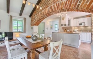 Enjoy meals in the kitchen with a microwave and stainless steel sink, adjacent to a dining area with a wooden table and chairs.