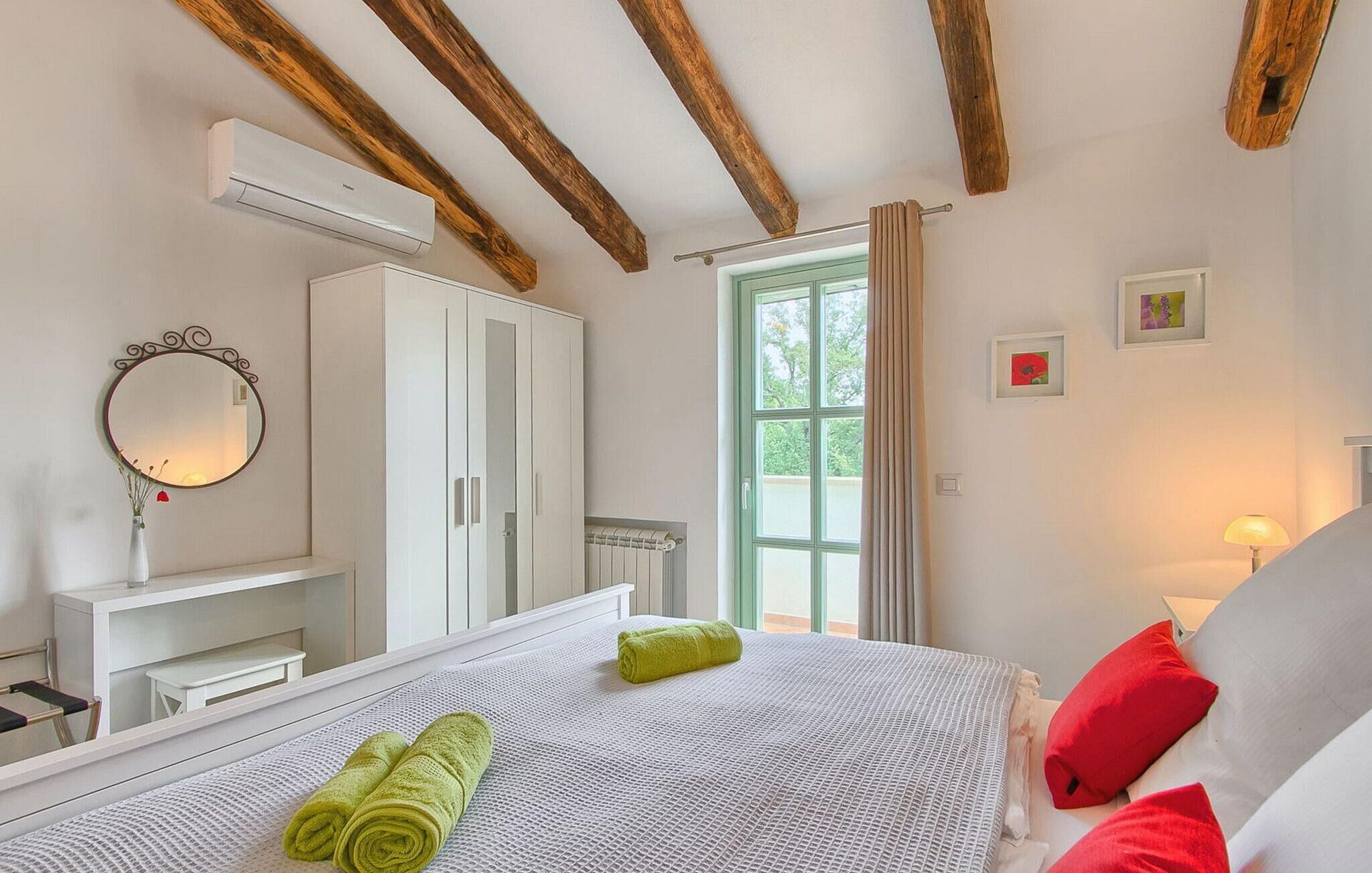 Una camera da letto con un letto, un armadio, uno specchio, un termosifone e una finestra con tende.