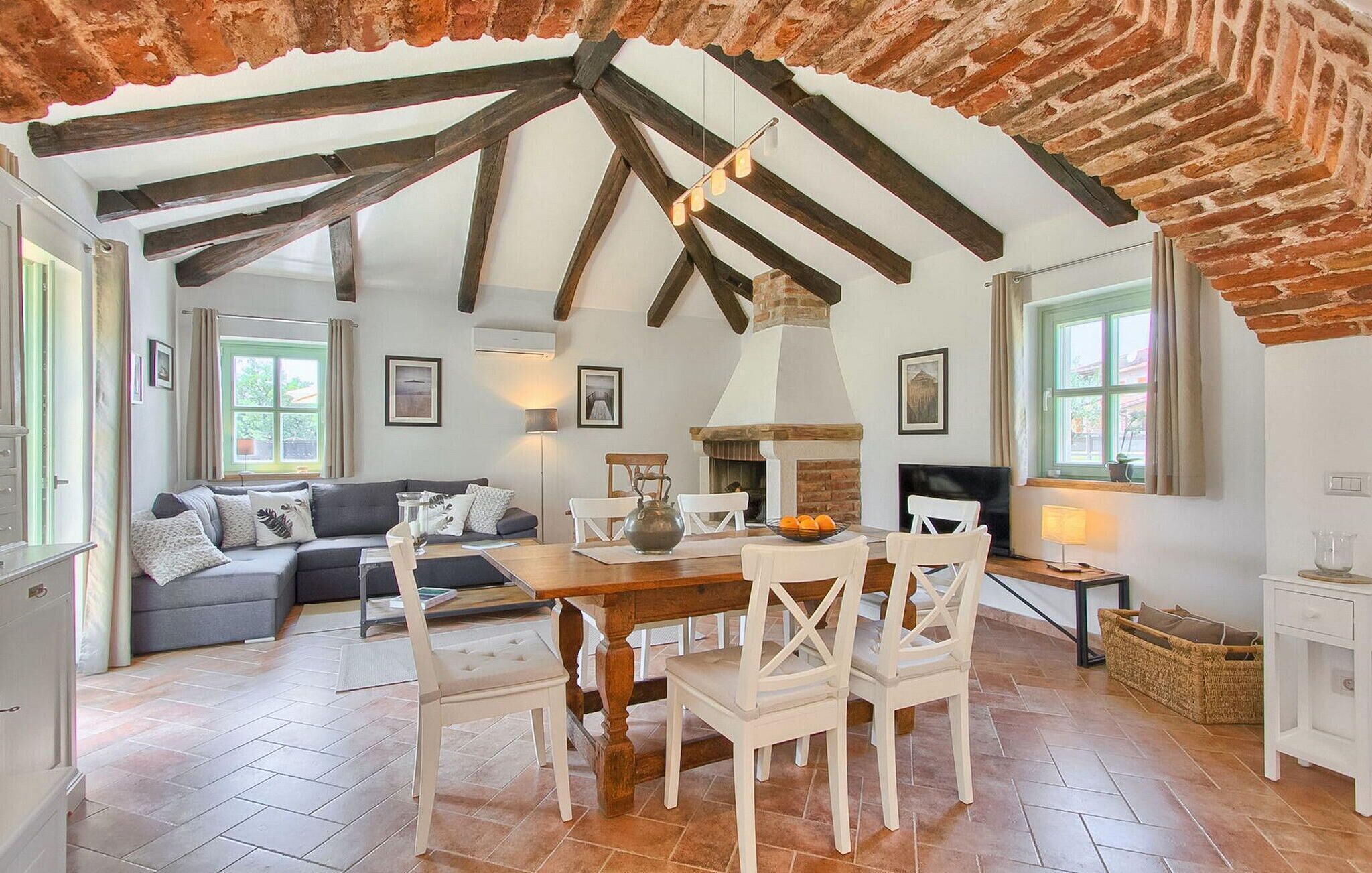 A dining area with a wooden table, white chairs, and a brick fireplace.