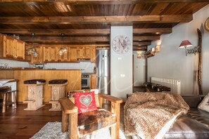 A rustic kitchen with wooden cabinets, a central island, and a large clock on the wall. - Urets (Bagergue)
