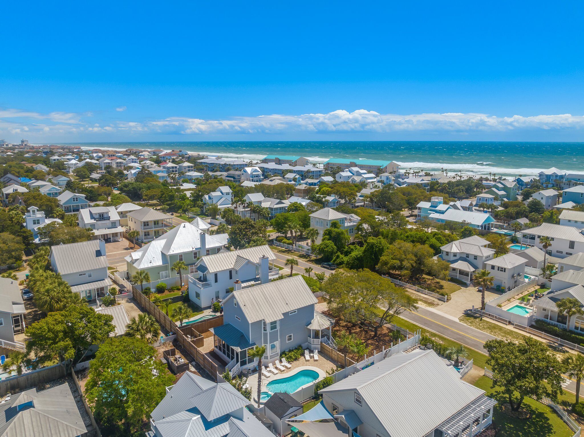 Un quartier résidentiel situé sur la côte, avec des maisons, une piscine et une vue sur l’océan.