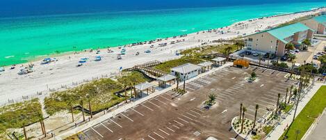 An aerial view of a beachside hotel with a parking lot, beach, and ocean.