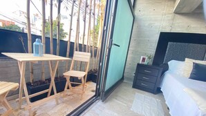Une chambre avec un lit, un petit bureau avec une chaise et une fenêtre donnant sur un jardin de bambous.