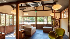 Una habitación amplia con un sofá, una silla verde y una estantería.