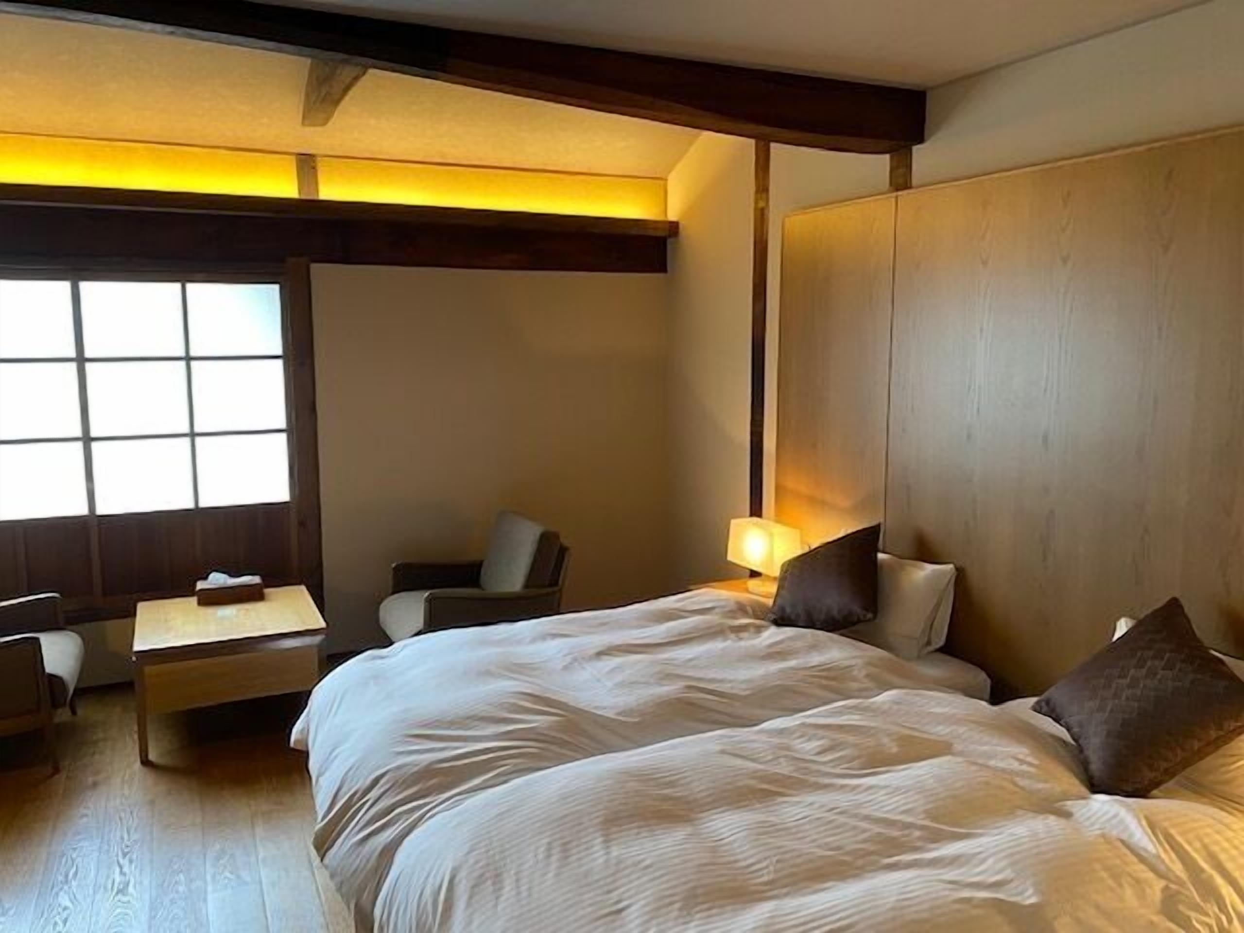 A hotel room with a large bed, a desk, a chair, and a window.