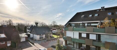 En modern bostadsbyggnad med flera balkonger, en parkeringsplats och en klar himmel.