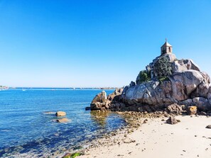A coastal landscape with a prominent rock formation and a small tower on top. - Chez Lucie by Interhome (Camlez)