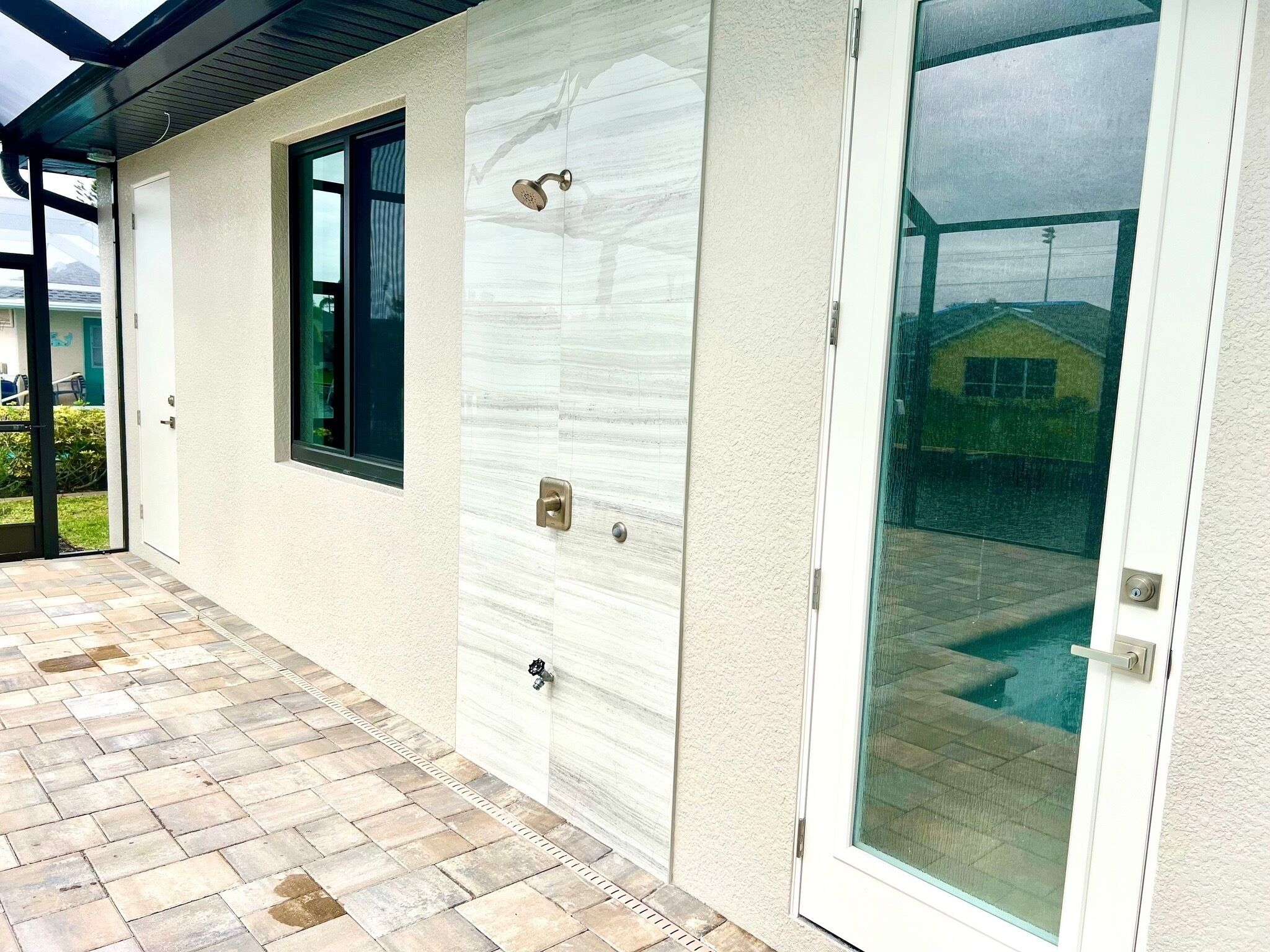 A covered patio with a tiled floor, a sliding glass door, and a window.