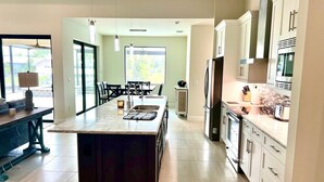 A modern kitchen with a central island, stainless steel appliances, and a dining area with a view.