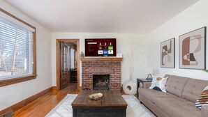 Una sala de estar con chimenea, televisor montado y sofá.