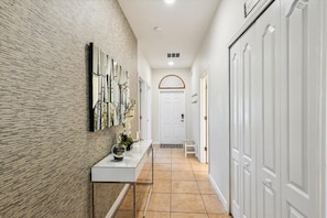 Un pasillo con pared texturizada, una puerta blanca y un armario blanco.