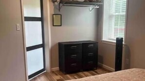 A bedroom with a bed, a dresser, a window, and a door. - Cozy Apartment located on our 5-acre property (Winchester)