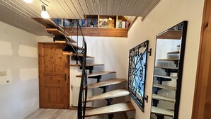 A wooden staircase with a metal railing leading to a loft area with bookshelves. - Vacation home Selma by Interhome (Grossschönau)