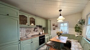 A kitchen with green cabinets, a wooden table, and a bench. - Vacation home Selma by Interhome (Grossschönau)