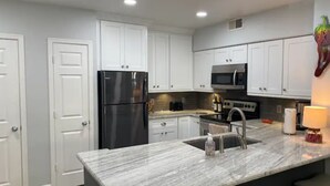 A modern kitchen with white cabinets, a black refrigerator, a stainless steel oven, and a marble countertop. - 2Bedroom/2Bath North Scottsdale Condo w/Amentities.

 (Scottsdale)
