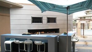 An outdoor bar area with a fire feature, bar stools, and a large umbrella. - 2Bedroom/2Bath North Scottsdale Condo w/Amentities.

 (Scottsdale)